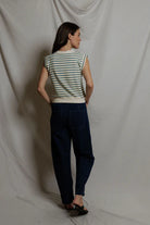 Woman wearing a striped shirt and dark pants against a plain background
