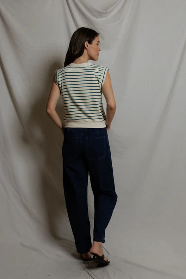 Woman wearing a striped shirt and dark pants against a plain background