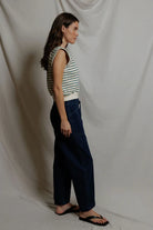 Woman wearing a striped sleeveless top and wide-leg pants against a plain background