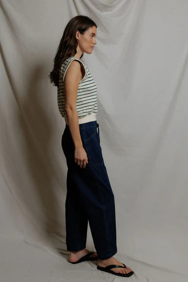 Woman wearing a striped sleeveless top and wide-leg pants against a plain background