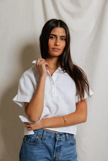Woman wearing a white shirt and blue jeans against a plain background