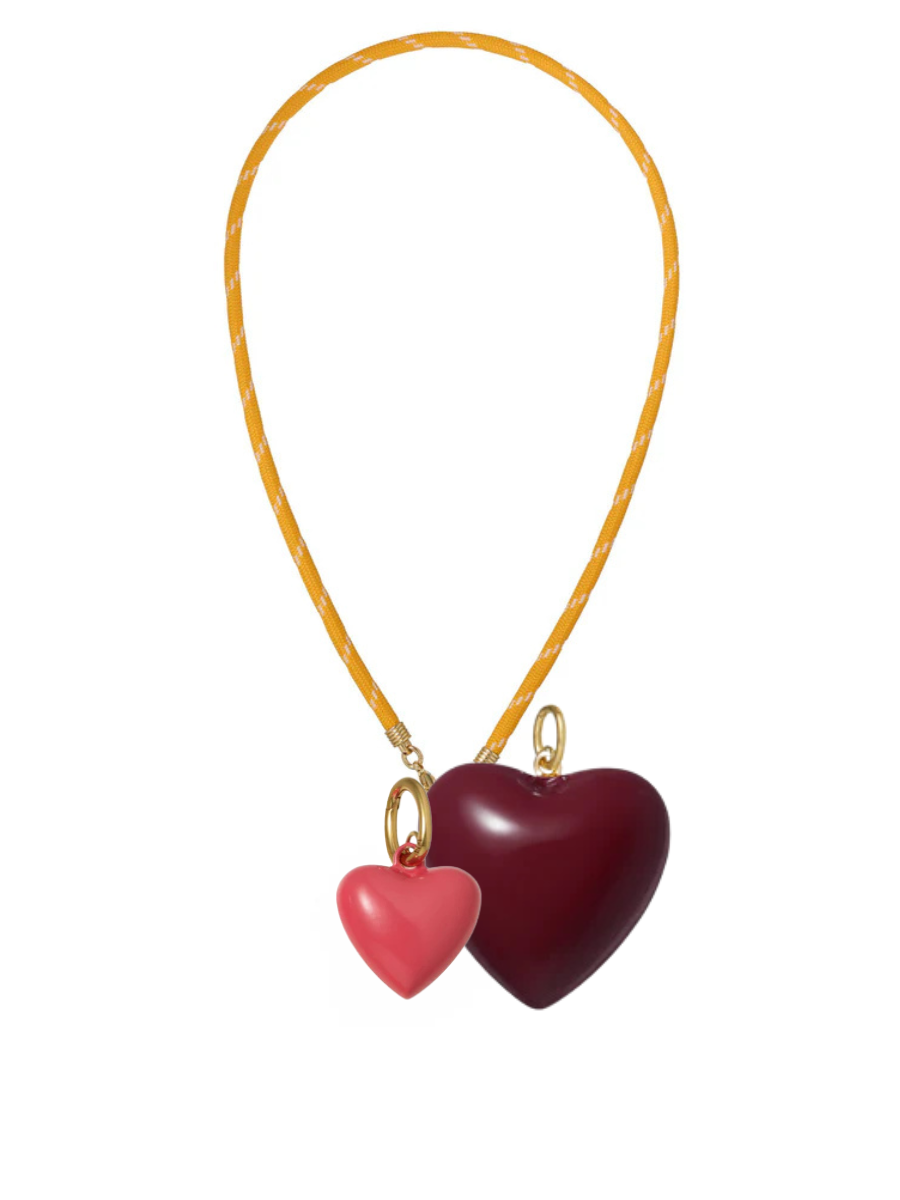 Necklace with two heart-shaped pendants on a yellow cord against a white background