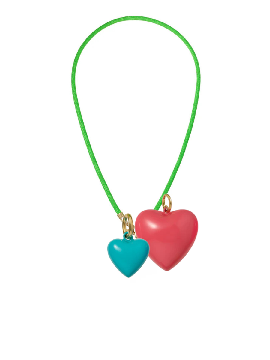 Necklace with two heart-shaped pendants, one red and one blue, on a green cord against a white background.