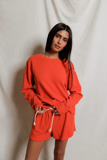 Woman wearing a bright orange outfit against a plain background
