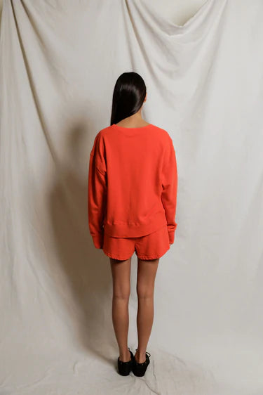 Person wearing an orange outfit standing against a plain white background