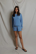 Woman wearing a blue outfit standing against a plain background