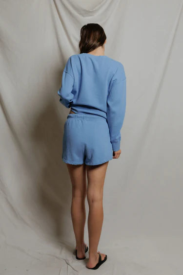 Person wearing a blue outfit standing against a plain background