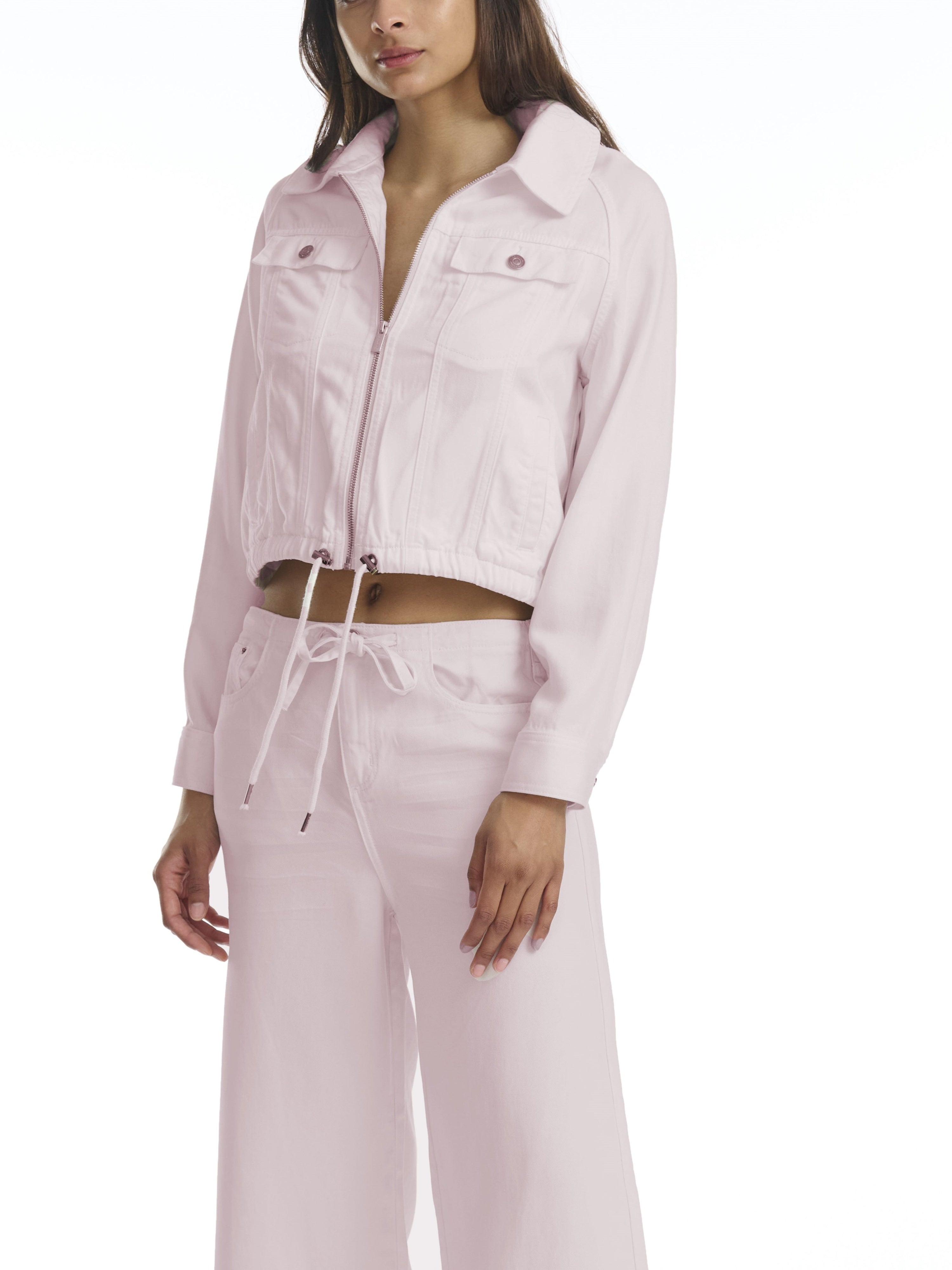 Woman wearing a light pink outfit with a jacket and pants on a white background