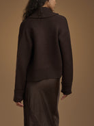 Person wearing a brown sweater against a matching background