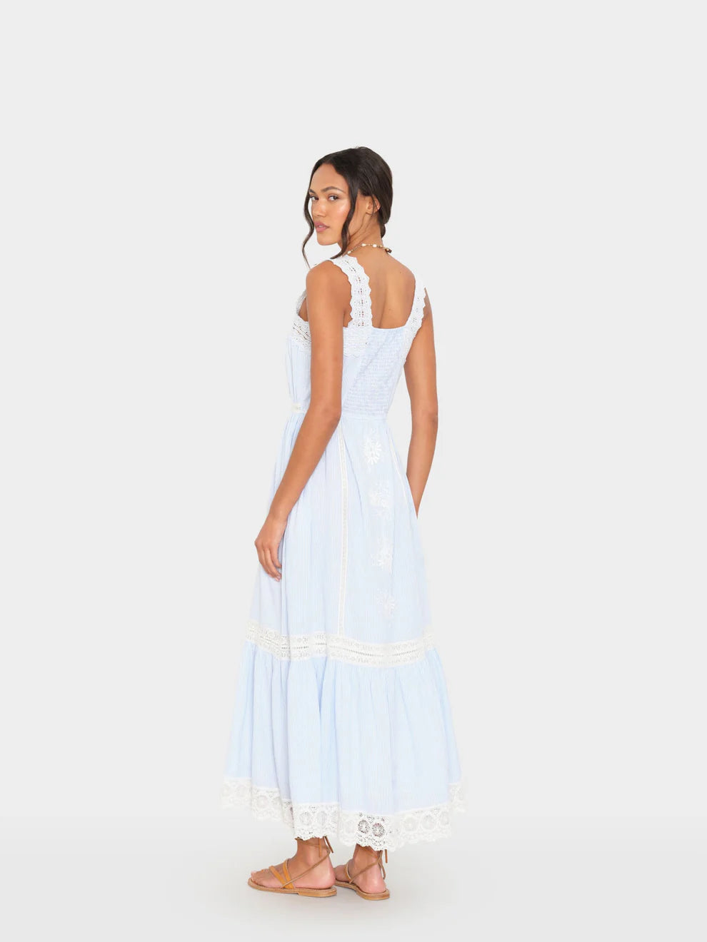 Woman wearing a light blue dress with white lace details on a white background