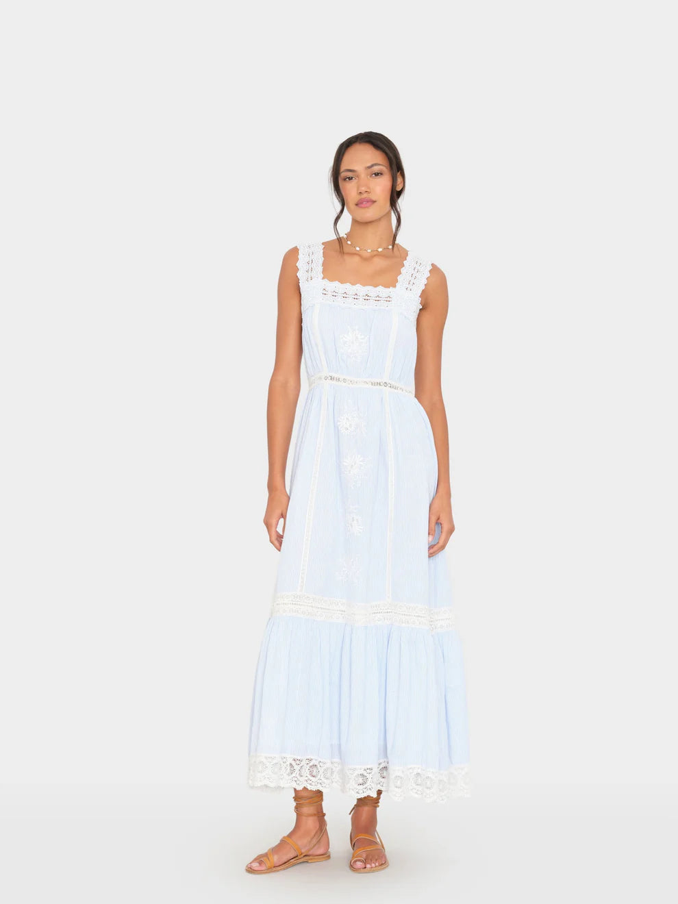 Woman wearing a light blue dress with lace details on a white background