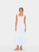 Woman wearing a light blue dress with lace details on a white background