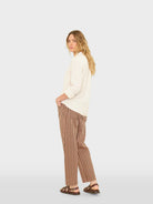 Woman wearing a white top and brown striped pants on a white background