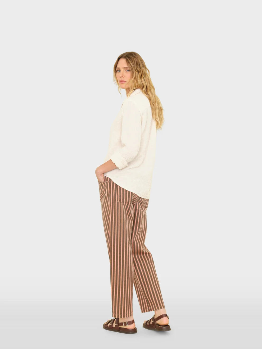 Woman wearing a white top and brown striped pants on a white background