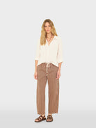 Woman wearing a cream blouse and striped pants on a white background