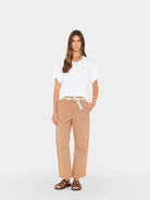 Woman wearing a white top and beige pants on a white background