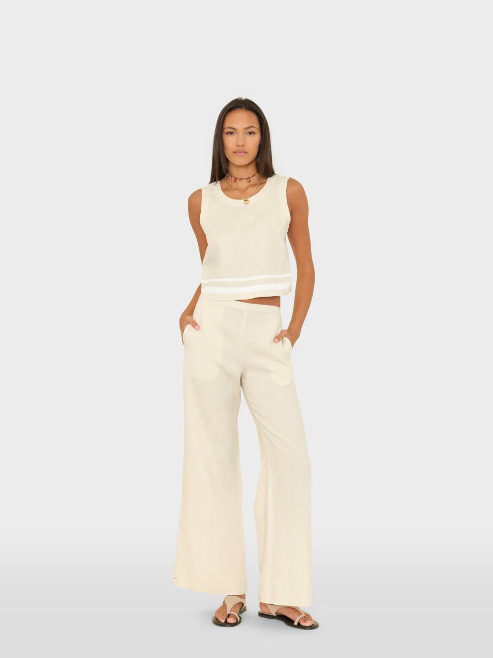 Woman wearing a white sleeveless top and wide-leg pants on a light gray background