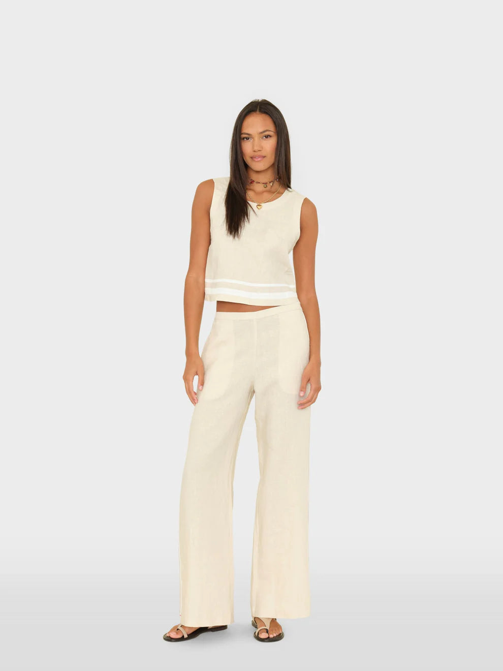 Woman wearing a white sleeveless top and wide-leg pants on a light gray background