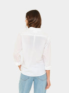 Woman wearing a white blouse and light blue jeans on a white background