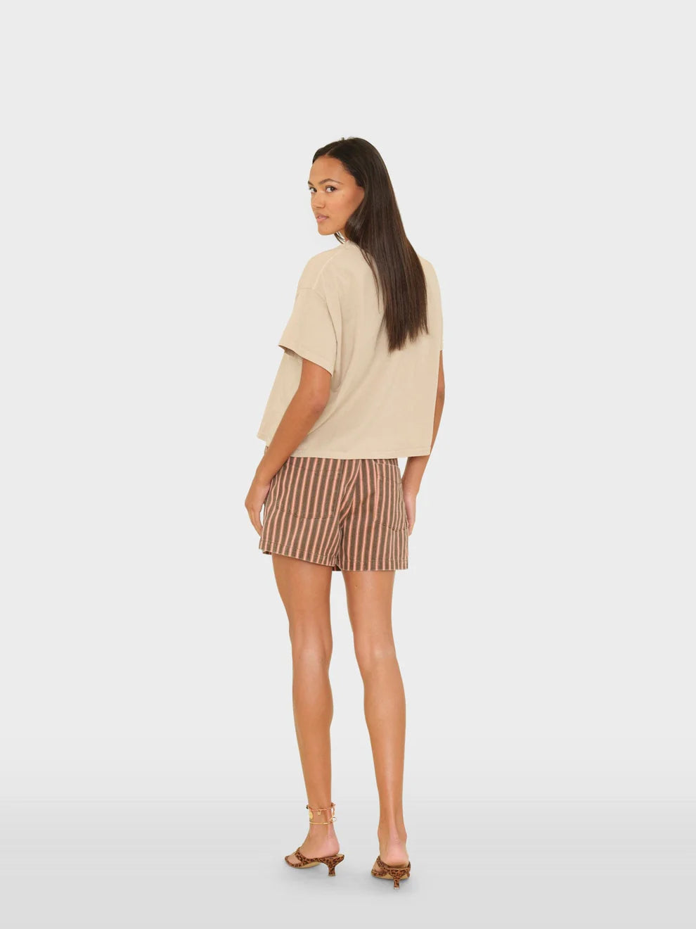 Woman wearing a beige top and striped shorts on a white background