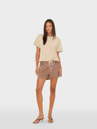 Woman wearing a beige top and striped shorts on a white background