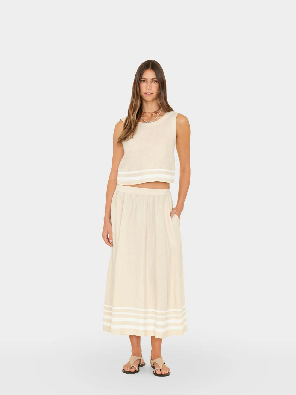 Woman wearing a white sleeveless top and skirt on a white background