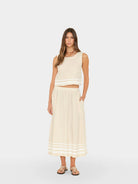 Woman wearing a white sleeveless top and skirt on a white background