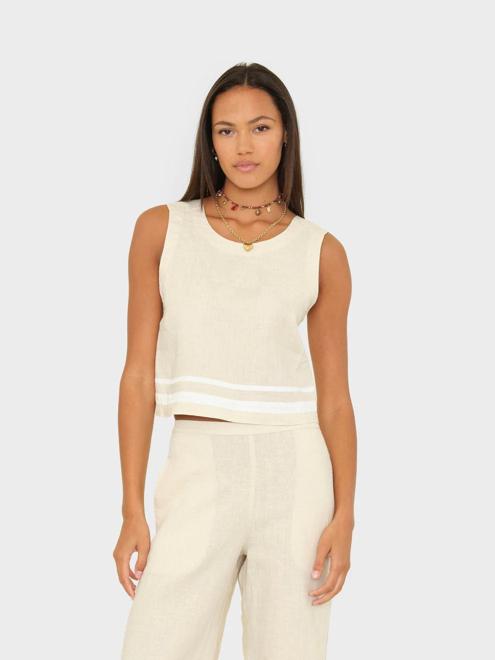 Woman wearing a cream sleeveless top and pants on a light gray background