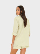 Woman wearing a light green ribbed top and shorts on a white background