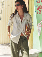 Woman wearing a striped shirt and green pants standing in front of a colorful sign.