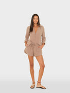 Woman wearing a beige romper on a white background