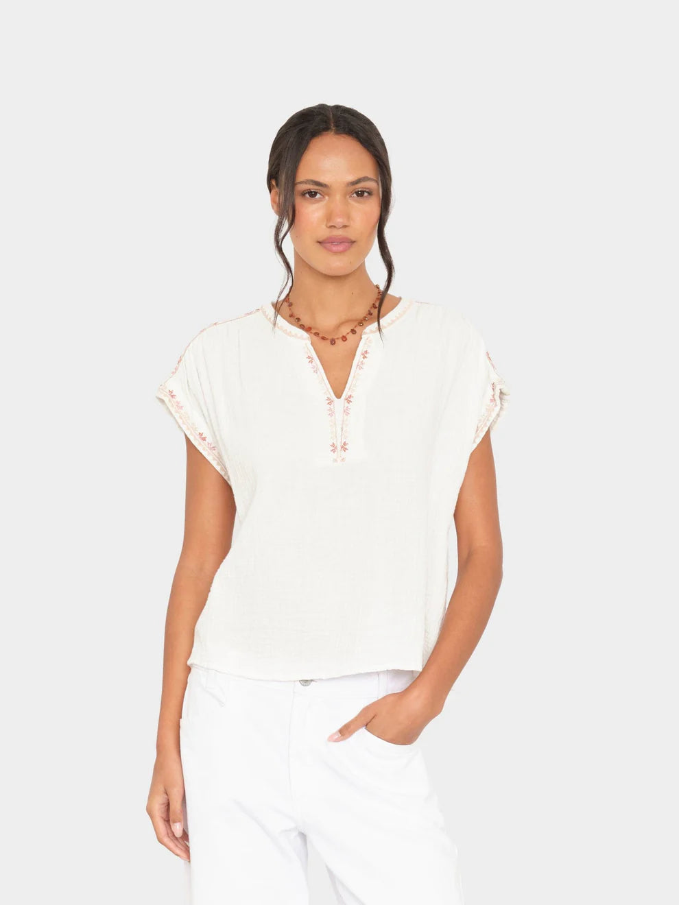 Woman wearing a white blouse with lace details on a plain background