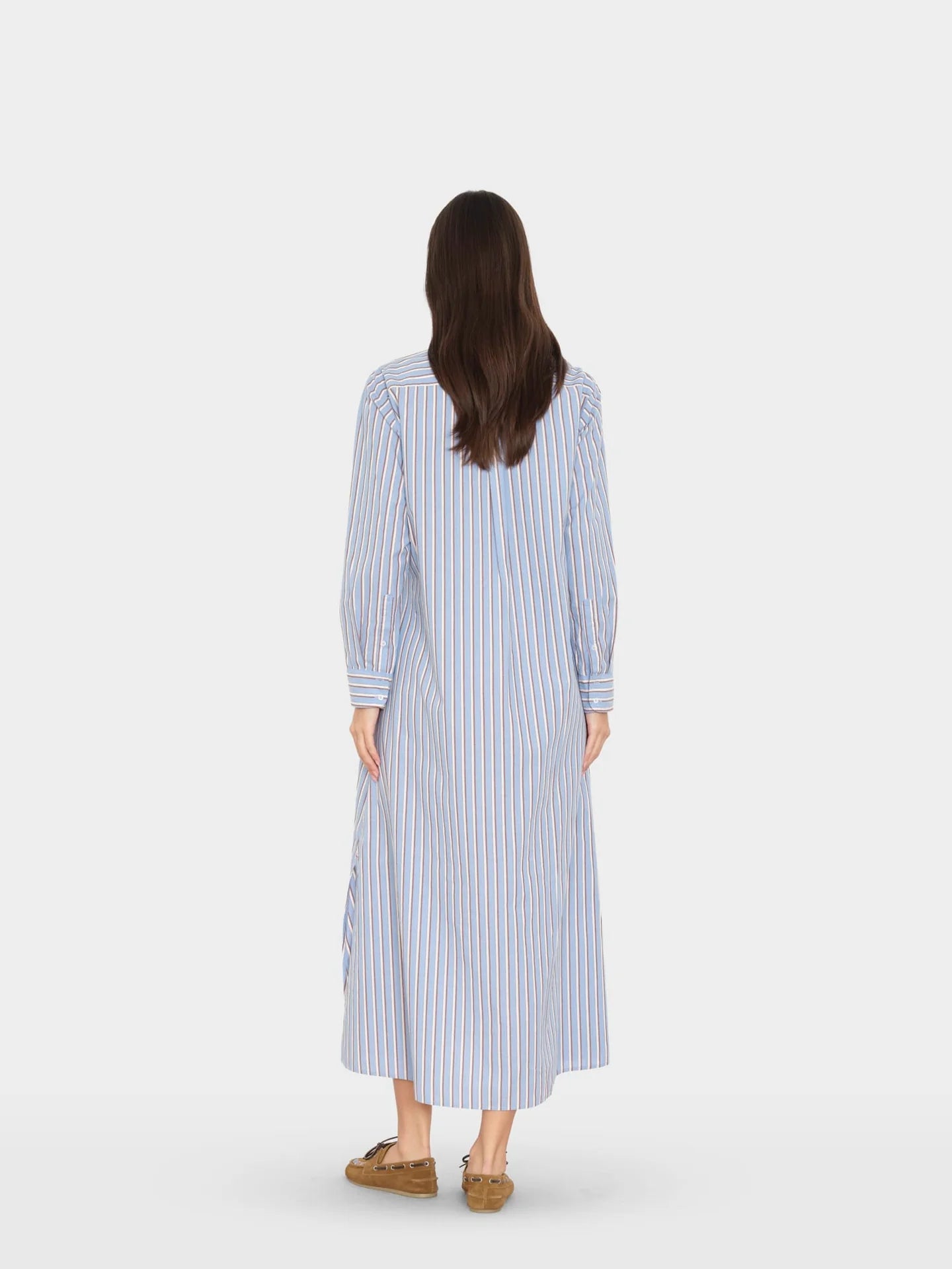 Woman wearing a long blue and white striped dress on a white background
