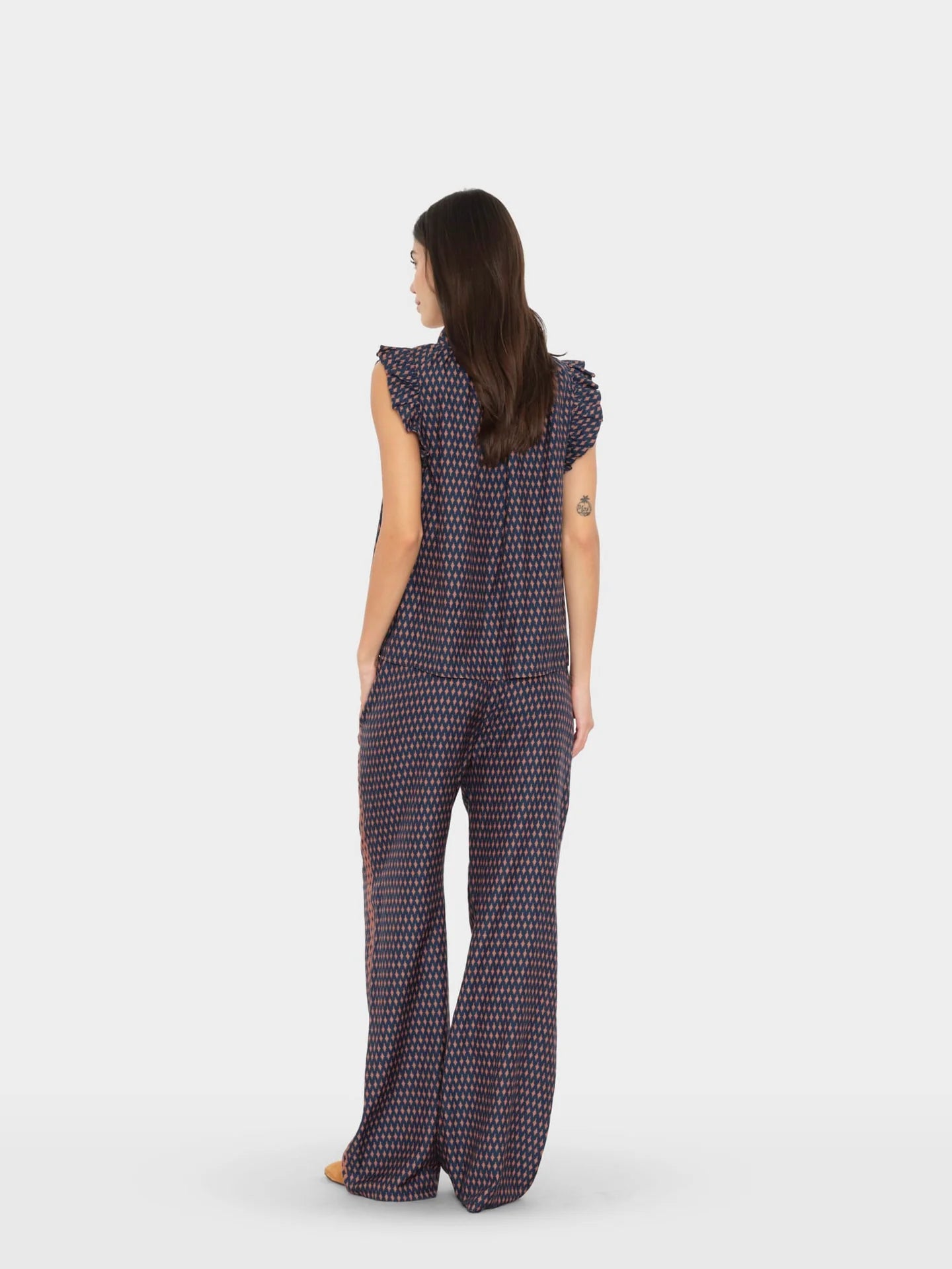 Woman wearing a patterned jumpsuit on a white background