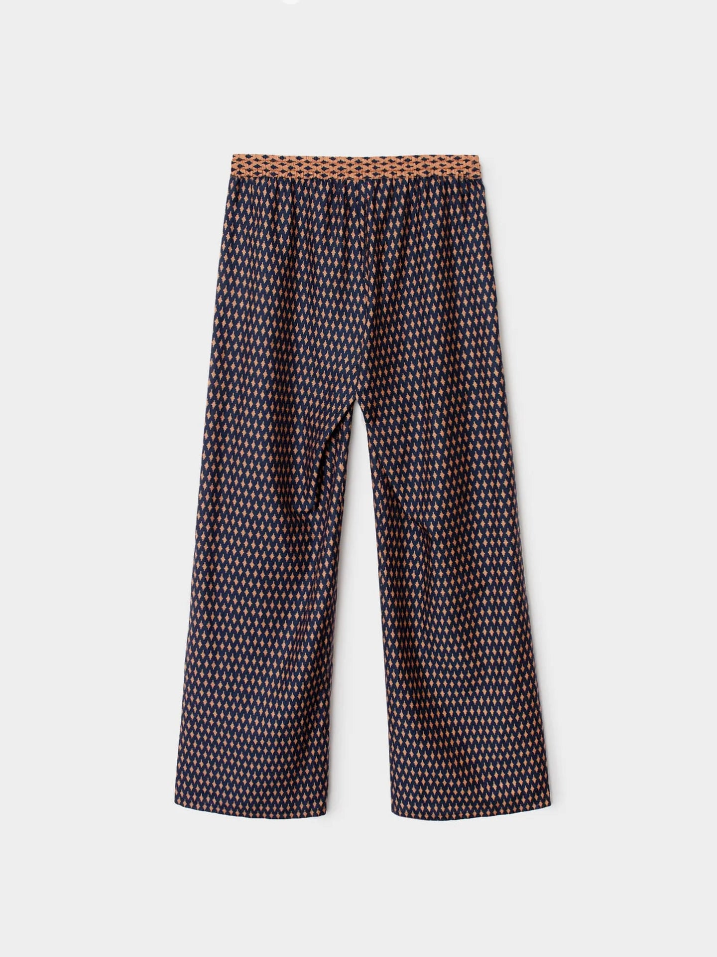 A pair of wide-leg cropped pants featuring a small-scale geometric pattern in dark brown, beige, and white, with a textured brown waistband, shown against a light gray background.