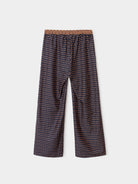 A pair of wide-leg cropped pants featuring a small-scale geometric pattern in dark brown, beige, and white, with a textured brown waistband, shown against a light gray background.