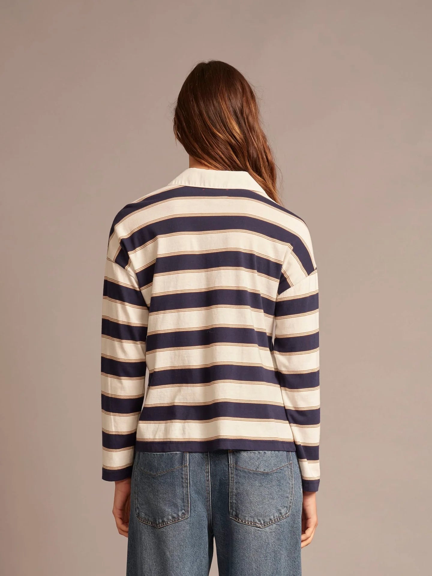 Person wearing a navy and white striped sweater with a plain background