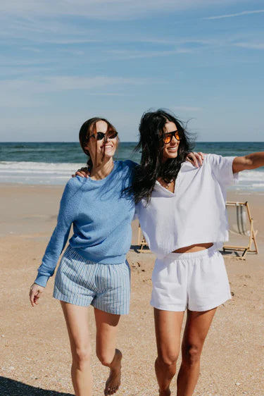 Two women walking on a beach with ocean in the background