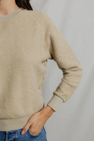 Beige sweater worn by a person on a plain background