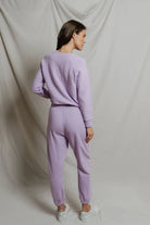 Person wearing a lavender tracksuit against a plain background