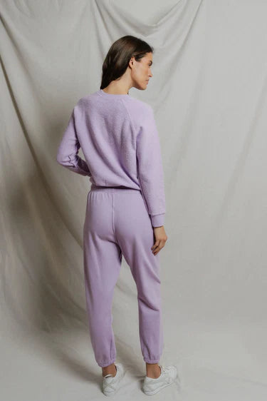 Person wearing a lavender tracksuit against a plain background